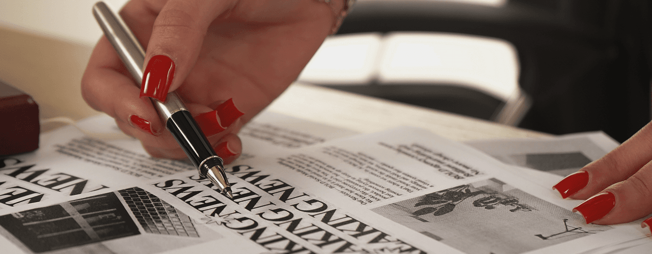 Editorial desk scene with a pen and red manicure